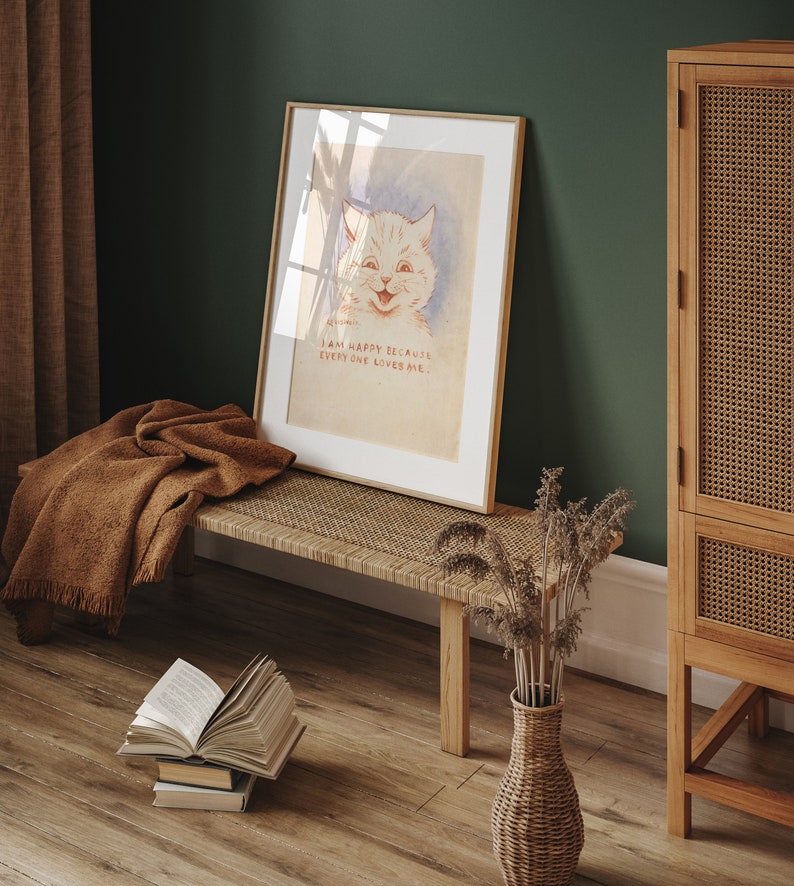 May include: A framed print of a white cat with a smiling face. The print has the text "I am happy because everyone loves me." The print is hanging on a green wall above a woven bench with a brown blanket draped over it. A wicker vase with dried flowers sits on the floor next to the bench.