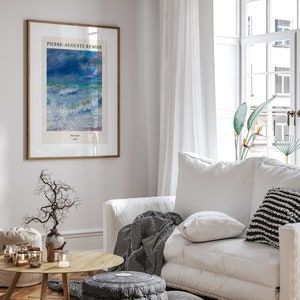 May include: A framed print of a painting by Pierre-Auguste Renoir titled "Seascape 1887". The painting depicts a seascape with blue and white waves crashing against the shore. The print is hanging on a white wall in a living room setting.