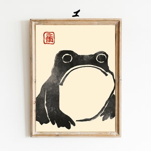 May include: A black and white illustration of a frog with a large, round belly. The frog is facing forward with its mouth closed. The illustration is on a cream-colored background with a red square in the top left corner that contains the Japanese character "春" (spring).
