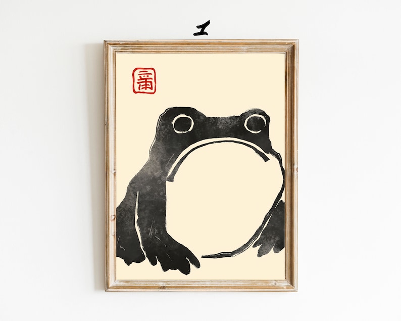 May include: A black and white illustration of a frog with a large, round belly. The frog is facing forward with its mouth closed. The illustration is on a cream-colored background with a red square in the top left corner that contains the Japanese character "春" (spring).