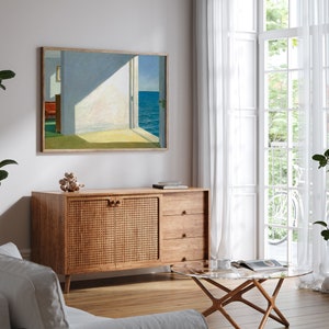May include: A mid-century modern living room featuring a wooden cabinet with a woven rattan door, a glass coffee table, and a framed painting depicting a seascape with an open door.