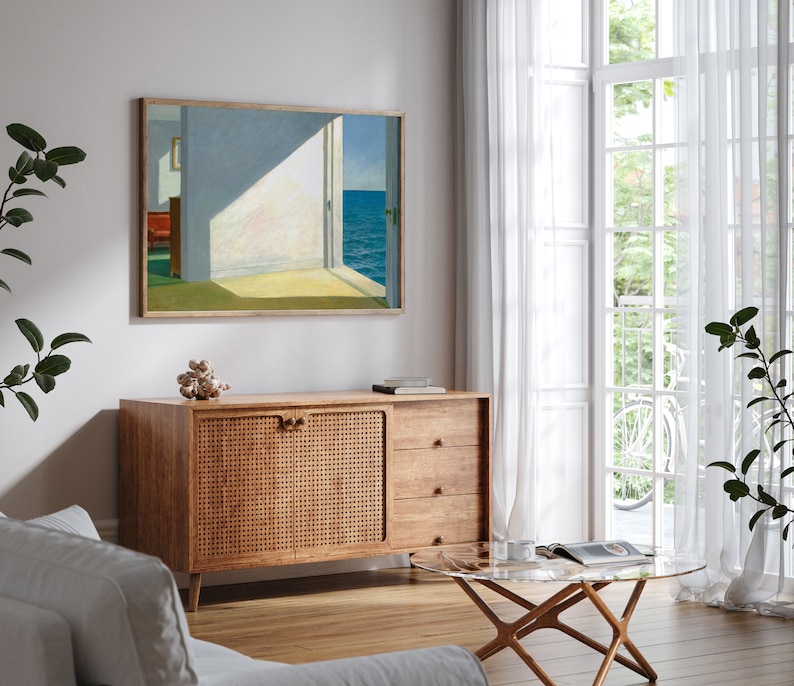 May include: A mid-century modern living room featuring a wooden cabinet with a woven rattan door, a glass coffee table, and a framed painting depicting a seascape with an open door.