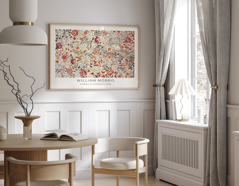 May include: A framed print of a floral pattern with the text "WILLIAM MORRIS - MORRIS & COMPANY, 1862" at the bottom. The print is hanging on a white wall in a room with a wooden table and chairs.
