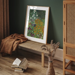 May include: A framed print of a painting depicting a field of colorful flowers. The flowers are mostly orange, yellow, and white, with some purple and blue accents. The background is a green field with a dark green forest in the distance.