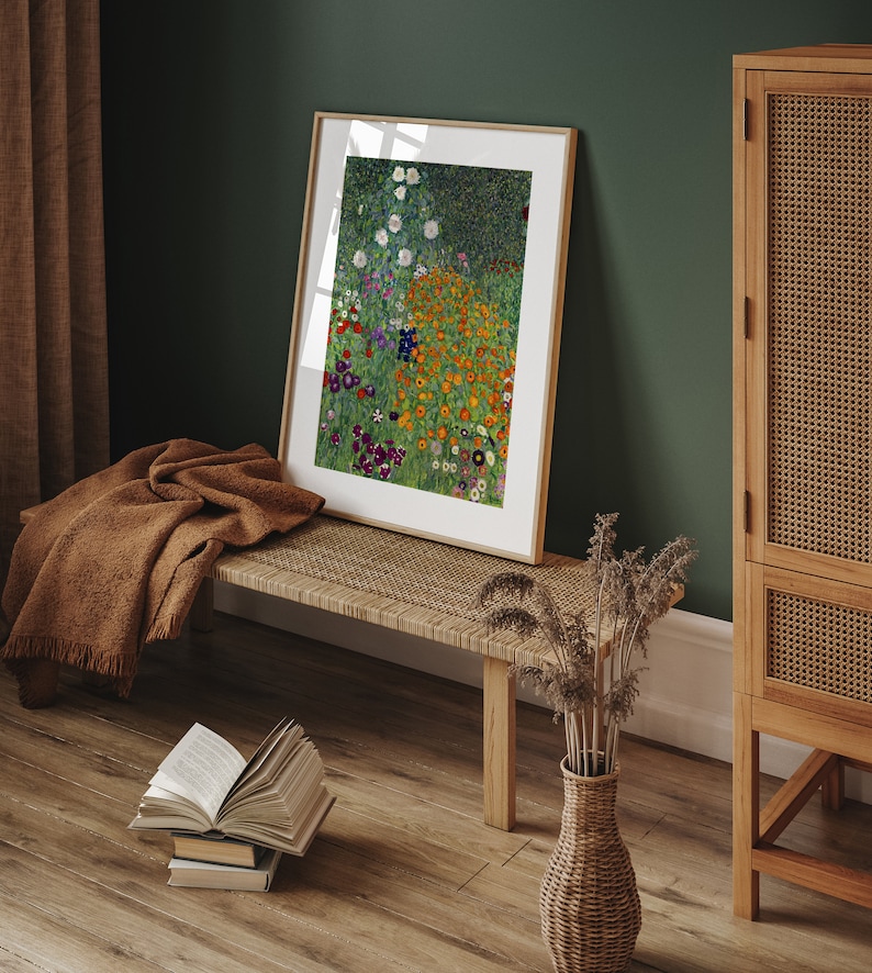 May include: A framed print of a painting depicting a field of colorful flowers. The flowers are mostly orange, yellow, and white, with some purple and blue accents. The background is a green field with a dark green forest in the distance.
