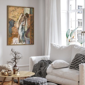 Peut inclure: Une peinture aux couleurs pastel d'une femme debout dans une salle de bain, partiellement v&ecirc;tue, avec une serviette &agrave; la main. La peinture est encadr&eacute;e et accroch&eacute;e &agrave; un mur blanc dans un salon.