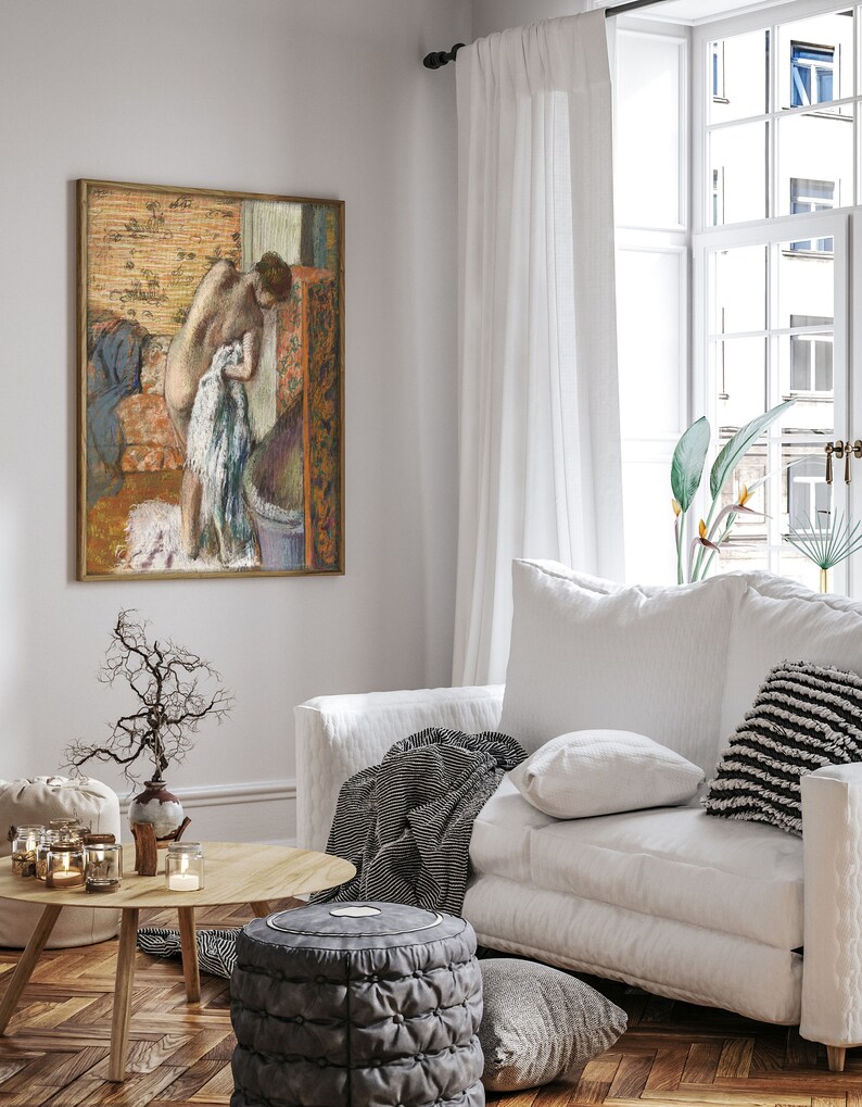 Peut inclure: Une peinture aux couleurs pastel d'une femme debout dans une salle de bain, partiellement v&ecirc;tue, avec une serviette &agrave; la main. La peinture est encadr&eacute;e et accroch&eacute;e &agrave; un mur blanc dans un salon.