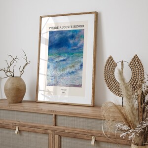 May include: A framed print of a seascape painting by Pierre-Auguste Renoir. The painting depicts a stormy sea with white-capped waves and a blue sky with clouds. The text "Seascape 1887" is printed below the painting.