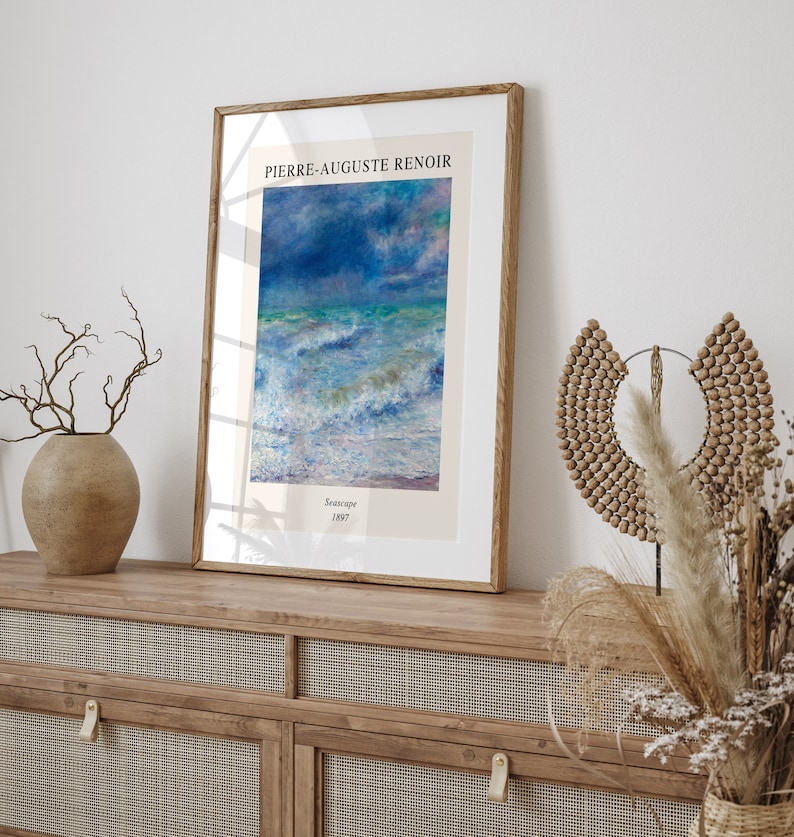 May include: A framed print of a seascape painting by Pierre-Auguste Renoir. The painting depicts a stormy sea with white-capped waves and a blue sky with clouds. The text "Seascape 1887" is printed below the painting.