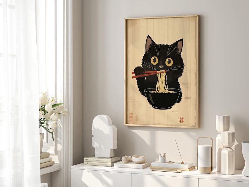 Puede incluir: Un gato negro con grandes ojos amarillos est&aacute; comiendo fideos de un taz&oacute;n con palillos. El gato est&aacute; sentado sobre un fondo de madera con texto japon&eacute;s.