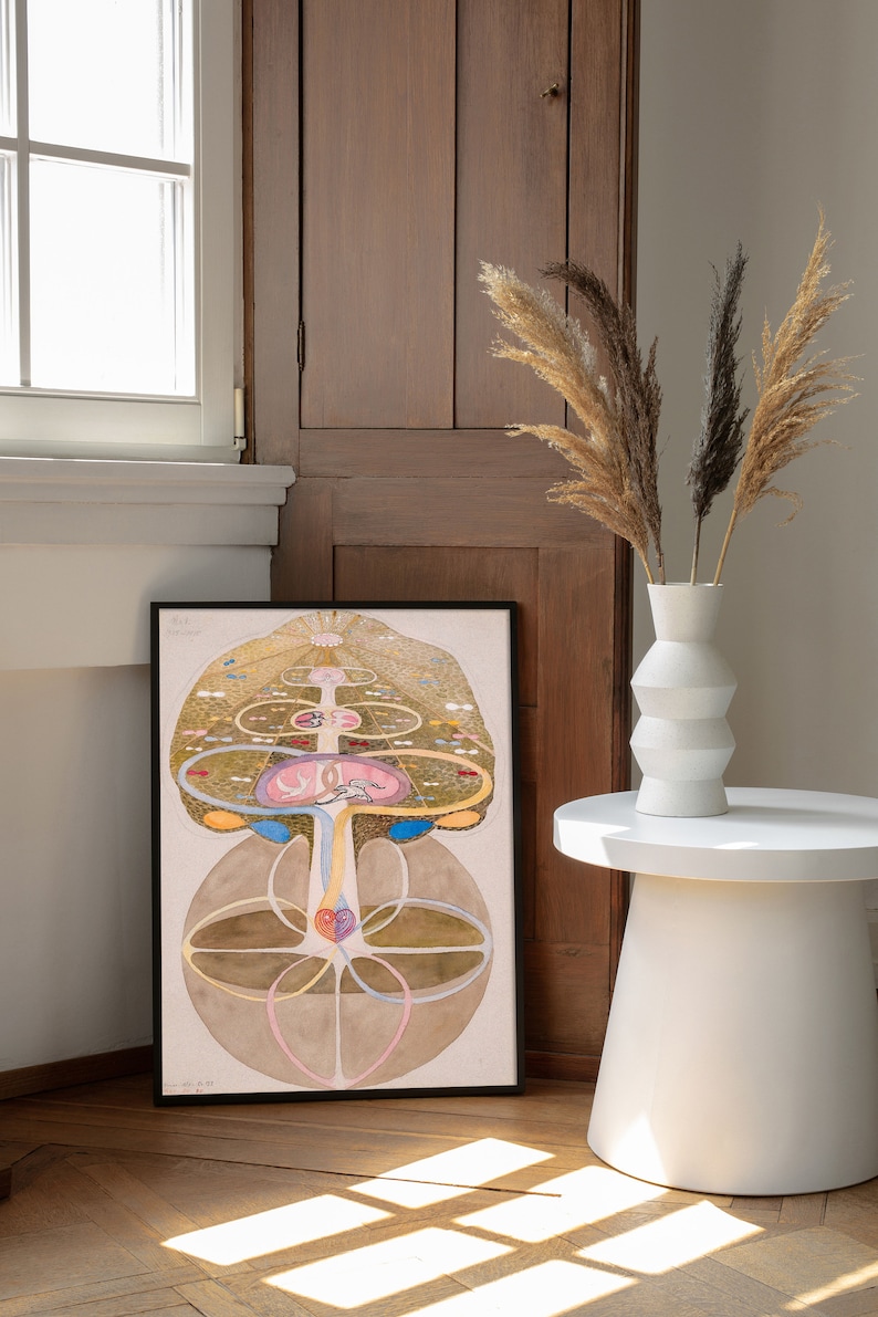 May include: A framed print of a detailed illustration of a tree of life with intricate branches, leaves, and roots. The tree is surrounded by circles and other geometric shapes, and the colors are mostly shades of brown, gold, and pink.