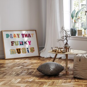 Puede incluir: Una impresi&oacute;n enmarcada con el texto "PLAY THAT FUNKY MUSIC" en letras coloridas y juguetonas. La impresi&oacute;n est&aacute; colgada en una pared blanca sobre un suelo de madera con un patr&oacute;n de espiga.