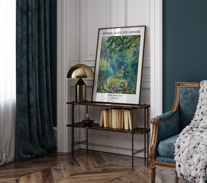 K&ouml;nnte beinhalten: Ein gerahmter Kunstdruck eines Gem&auml;ldes von Pierre-Auguste Renoir mit dem Titel "Sommertage im Bois" (1874-1877). Der Druck ist auf einem Regal mit einer goldenen Lampe und B&uuml;chern ausgestellt.