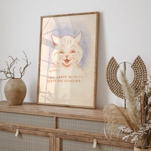 May include: A framed print of a white cat with a big smile. The cat is drawn in a vintage style with red and pink tones. The text below the cat reads "I am happy because everyone loves me."