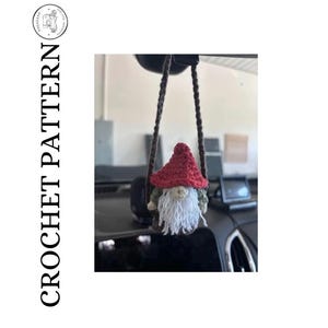 Könnte beinhalten: Ein gehäkelter Wichtel-Autoanhänger mit roter Mütze, weißem Bart und grün-braunem Körper. Der Wichtel hängt an einer braunen Schnur. Das Wort "CROCHET PATTERN" ist vertikal auf der linken Seite gedruckt.