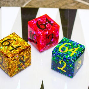 May include: Three glittery dice with the number 64 on each face. The dice are red, gold, and blue with iridescent glitter.