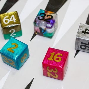 May include: Five different dice with various colors and numbers. The dice are made of resin and have a glossy finish. The numbers on the dice are 2, 16, 32, 64, and 8.