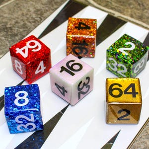 May include: Six glittery dice with white numbers are arranged on a black and white surface. The dice are red, blue, orange, green, pink, and gold. Each die has a different set of numbers, such as 4, 8, 16, 32, and 64. These dice are likely used for a board game.