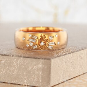 May include: A gold band ring with a heart design set with diamonds. The heart is surrounded by smaller diamonds and baguette-shaped diamonds.