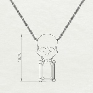 Puede incluir: Un collar plateado con un colgante de calavera y una gema rectangular. El colgante mide 1,67 cm de largo. La calavera est&aacute; encima de la gema, con una cadena delicada.