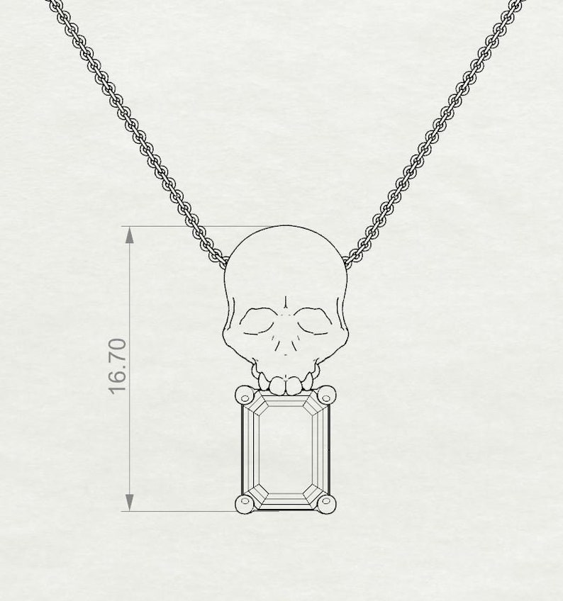 Puede incluir: Un collar plateado con un colgante de calavera y una gema rectangular. El colgante mide 1,67 cm de largo. La calavera est&aacute; encima de la gema, con una cadena delicada.