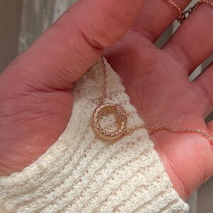 May include: A rose gold necklace featuring a snake-shaped pendant. The pendant is a circle with a snake wrapped around it.