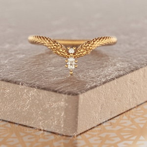 May include: A gold ring with a snake design and a single diamond in the center.