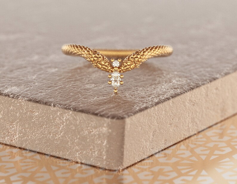May include: A gold ring with a snake design and a single diamond in the center.