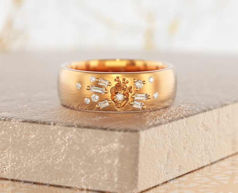 May include: A gold band ring with a heart design set with diamonds. The heart is surrounded by smaller diamonds and baguette-shaped diamonds.