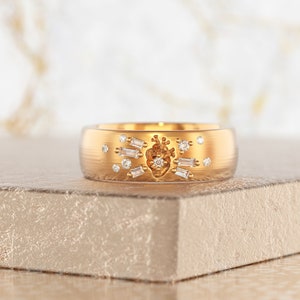May include: A gold band ring with a heart design and small diamonds set around it.