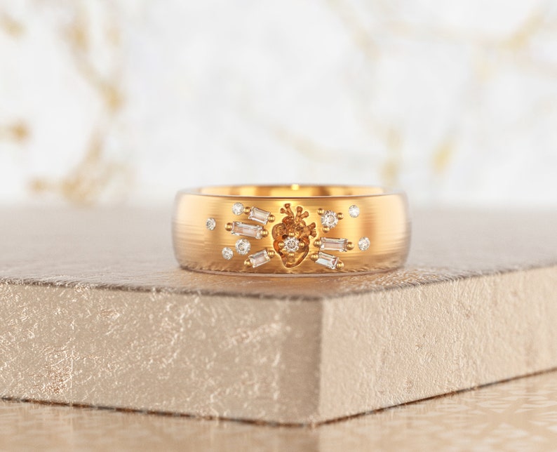 May include: A gold band ring with a heart design and small diamonds set around it.