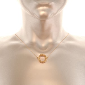 May include: A gold necklace with a circular pendant. The pendant is made of woven gold and has a smooth, polished finish.