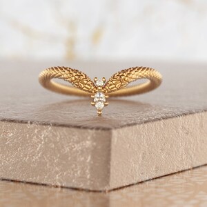 May include: A gold ring with a textured snake design and a small diamond in the center.
