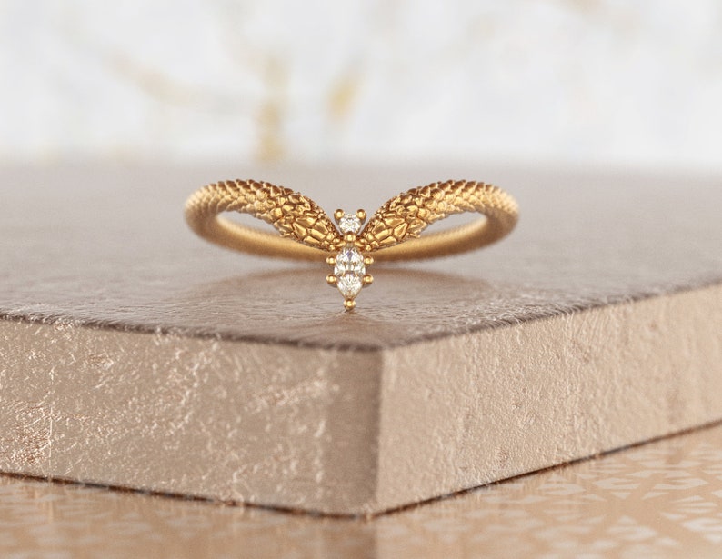 May include: A gold ring with a textured snake design and a small diamond in the center.