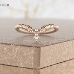 May include: A white gold ring with a textured snake design and a single diamond in the center.