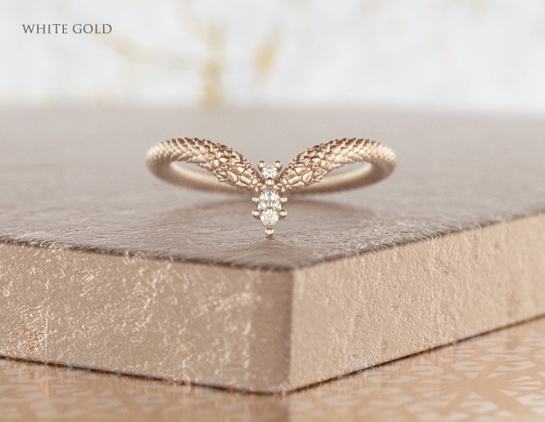 May include: A white gold ring with a textured snake design and a single diamond in the center.