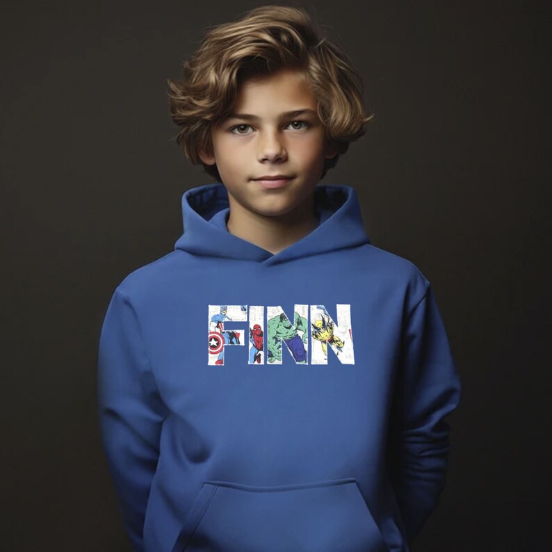 May include: A blue hooded sweatshirt with the name "FINN" printed in white letters. The letters are filled with images of various superheroes, including Spiderman, Hulk, and Captain America.