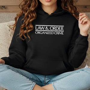 May include: Black hooded sweatshirt with white text that reads "Law & Order Organized Crime".