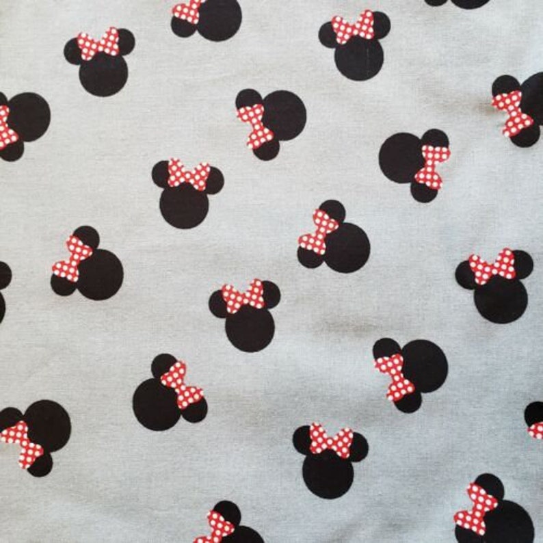 May include: Pale grey fabric featuring a repeating pattern of black mouse silhouettes adorned with red and white polka dot bows. The design is evenly distributed, creating a playful and familiar motif.