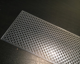 May include: A silver metal sheet with a repeating pattern of small, rounded shapes. The sheet is slightly curved and has a shiny finish.