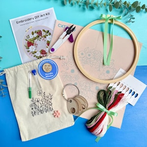 May include: An embroidery DIY art kit. The kit includes a wooden embroidery hoop, coloured threads, a needle minder, a canvas bag with a floral design, scissors, and a pattern. The text "Embroidery DIY Art Kit" is visible.