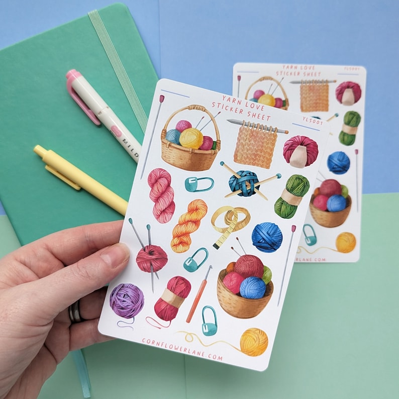 May include: A sticker sheet with colorful illustrations of yarn, knitting needles, and other craft supplies. The sheet is titled "Yarn Love Sticker Sheet" and includes the website "cornflowerlane.com".
