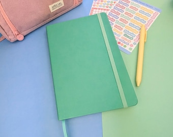 May include: A solid mint green notebook with an elastic closure band and a matching ribbon bookmark. Beside it lies a yellow pen and a sheet of colorful planner stickers labeled Sorbet Functional Planner and Sorbet Week Planner Stickers.