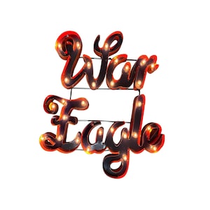May include: A decorative sign with the words "War Eagle" in a cursive font. The letters are outlined in black with red accents and illuminated by small, warm-toned light bulbs. The sign is mounted on a black wire frame.