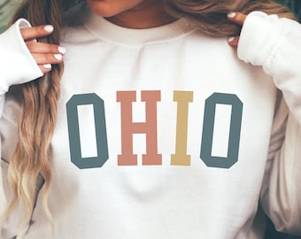 May include: White sweatshirt with the word "OHIO" printed in colourful block letters.