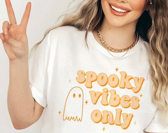May include: White t-shirt with a ghost graphic and the text "spooky vibes only" in orange letters.