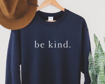 Könnte beinhalten: Ein marineblauer Pullover mit dem Aufdruck "be kind." in Weiß auf der Vorderseite.