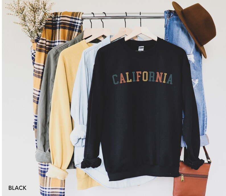 Puede incluir: Sudadera negra con la palabra "CALIFORNIA" impresa en letras de colores en la parte delantera.