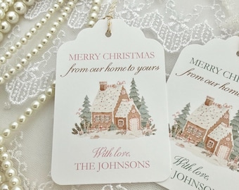 May include: Two white rectangular gift tags with scalloped tops and gold string. Each tag features a watercolor illustration of a snow-covered gingerbread house and pine trees. Text reads: MERRY CHRISTMAS from our home to yours With love, THE JOHNSONS.