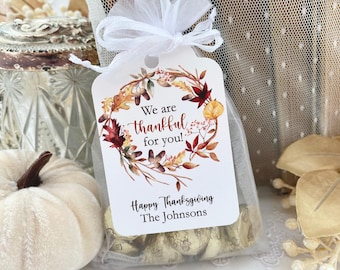 May include: A white rectangular gift tag with rounded corners attached to a sheer white organza drawstring bag. The tag features a watercolor autumn leaf wreath, the text We are thankful for you!, Happy Thanksgiving, and The Johnsons.